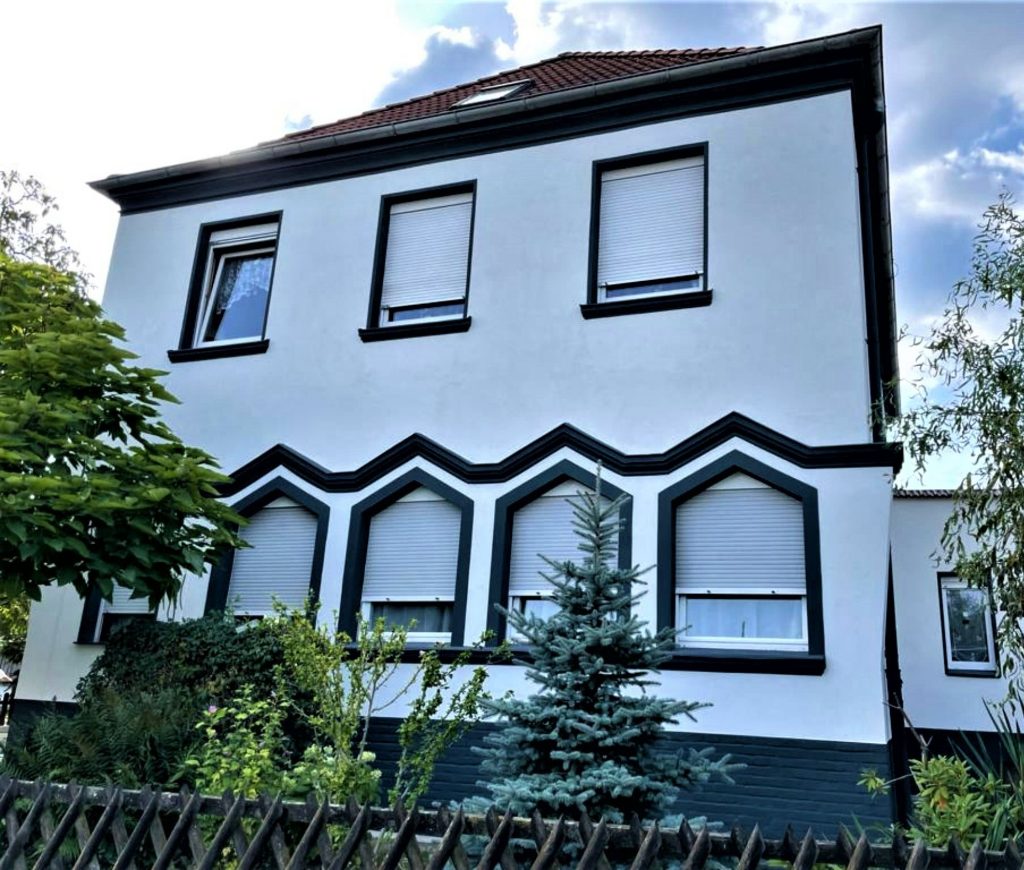 Ein frisch renoviertes Gebäude in Schwedt mit klaren, weißen Fassaden und kontrastierenden schwarzen Fensterrahmen, die die hochwertige Arbeit von Abauservice im Bereich Fassadenarbeiten in Schwedt demonstrieren.
