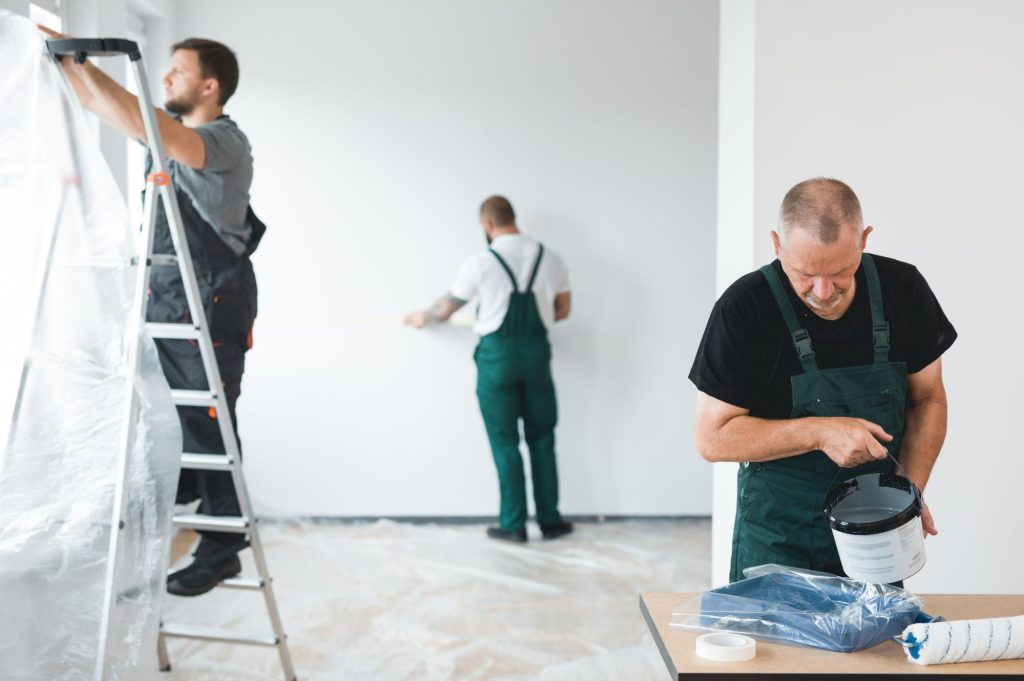 Arbeiter einer Baufirma in Schwedt führen Wohnungssanierungsarbeiten durch, einschließlich Streichen und Vorbereiten der Wände.